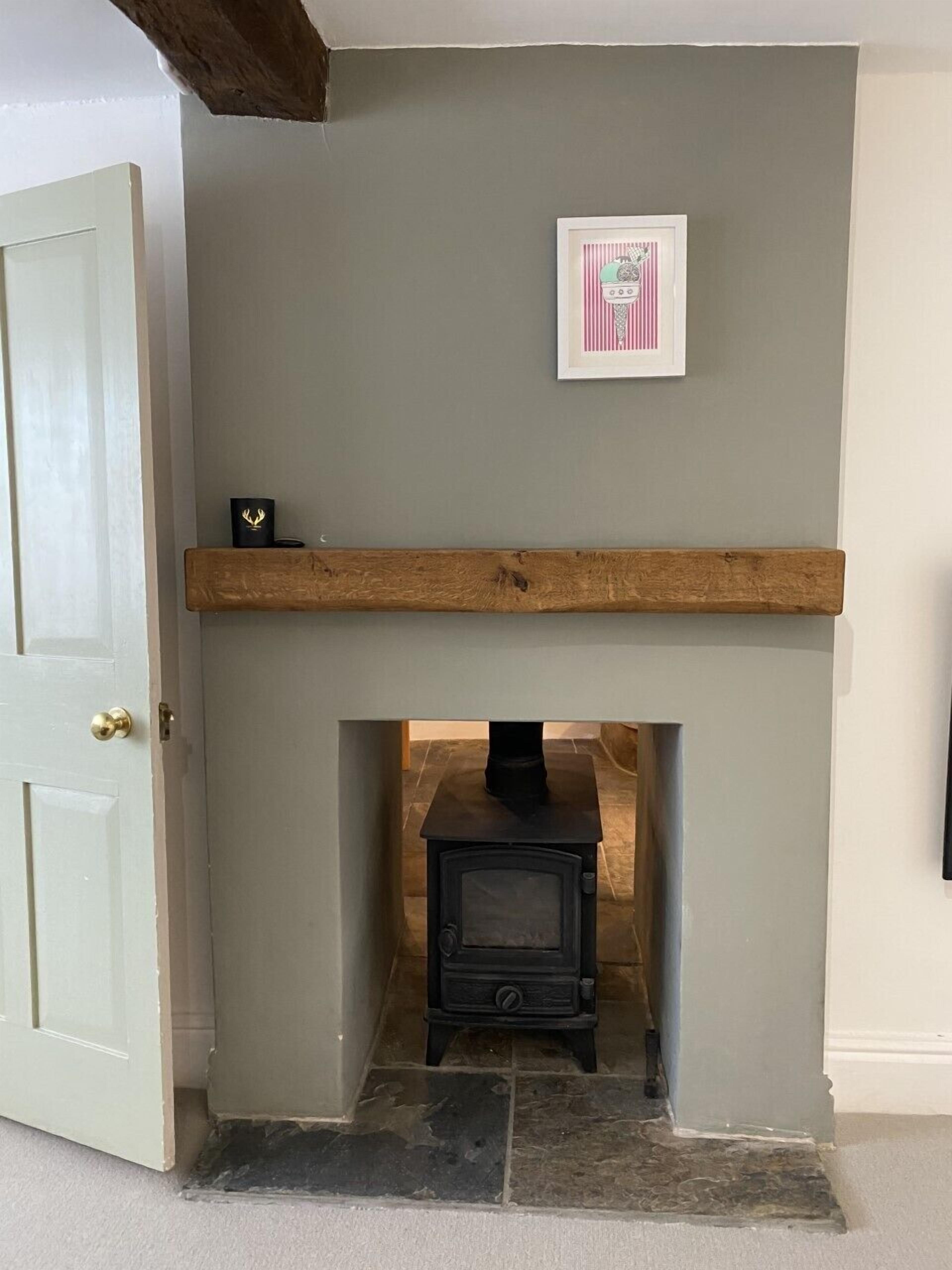 A room with a fireplace, a wooden shelf, and a framed picture on the wall.