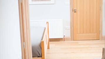 Una stanza con una porta in legno, un termosifone e un quadro appeso al muro.