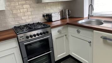 A kitchen with white cabinets, a black stove, and a sink.