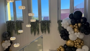 Eine Treppe mit Glastrennstäben, einer Kristallleuchtre und einer Wand, die mit schwarzen, weißen und goldenen Ballons geschmückt ist.