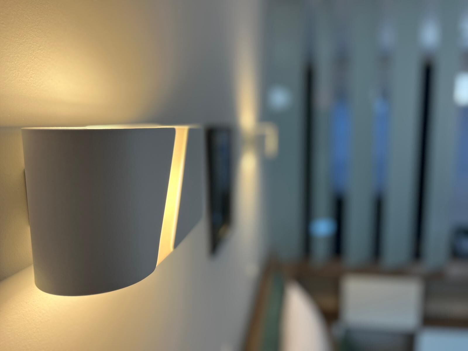 Et moderne interiør med en vægmonteret lampe og en uskarpt baggrund, der antyder et offentligt rum.
