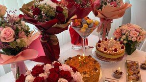 Ein Tisch reichhaltig gedeckt mit verschiedenen Blumenarrangements, einer Torte und Desserts.