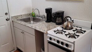 A kitchen with a white stove, a sink, and a coffee maker. - Stylish Retreat w/ Queen Bed • Fast WiFi • Free Parking (Colorado Springs)