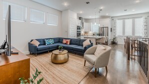 A modern living room with a blue sectional sofa, a round coffee table, and a grey armchair. - Contemporary Home with Office, Centrally Located (Plano)