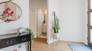 A hallway with a black console table, a mirror, and a potted plant. - Contemporary Home with Office, Centrally Located (Plano)