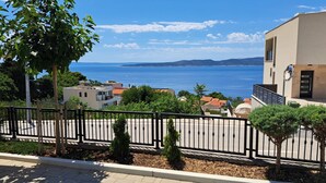 A coastal residential area with a paved road, a metal fence, and buildings with balconies overlooking the sea. - Room in Brela with Seaview, Terrace, Air condition, WIFI (4947-2) (Brela)