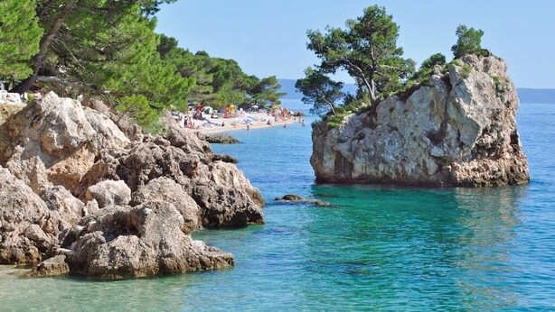 A coastal scene with clear turquoise water, rocky formations, and pine trees. - Room in Brela with Seaview, Terrace, Air condition, WIFI (4947-2) (Brela)