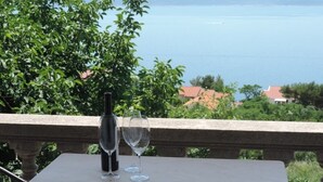 A table with a bottle and two glasses on a balcony overlooking a body of water and buildings. - Room in Brela with Seaview, Terrace, Air condition, WIFI (4947-2) (Brela)
