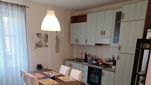 A modern kitchen with white cabinets, a dining area with a table set for two, and a striped rug on the floor. - Holiday home in the Palazzo dei Normanni area and historic center. (Palermo)