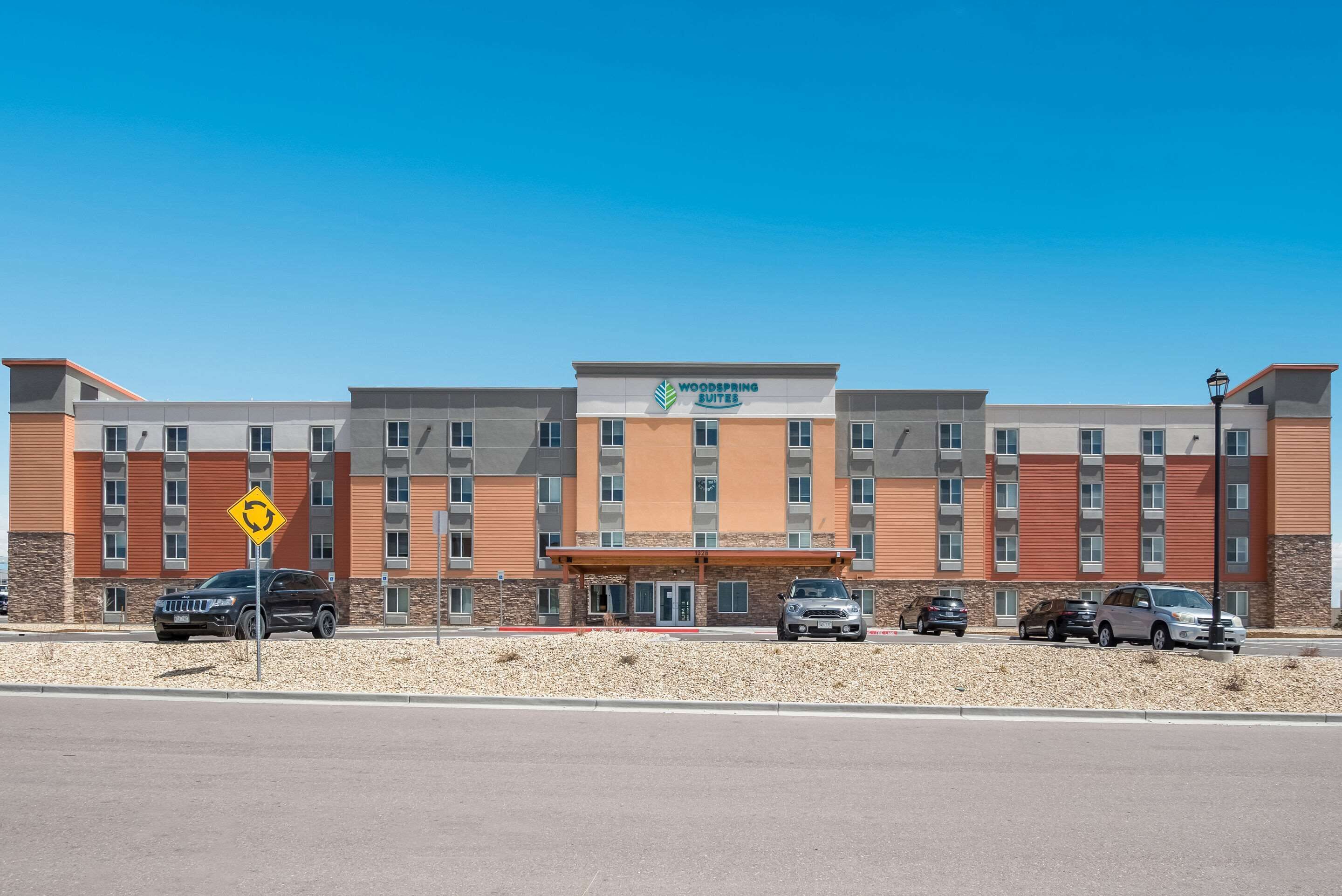 Un hotel de varios pisos con entrada central y un letrero que dice "Woodspring Suites".