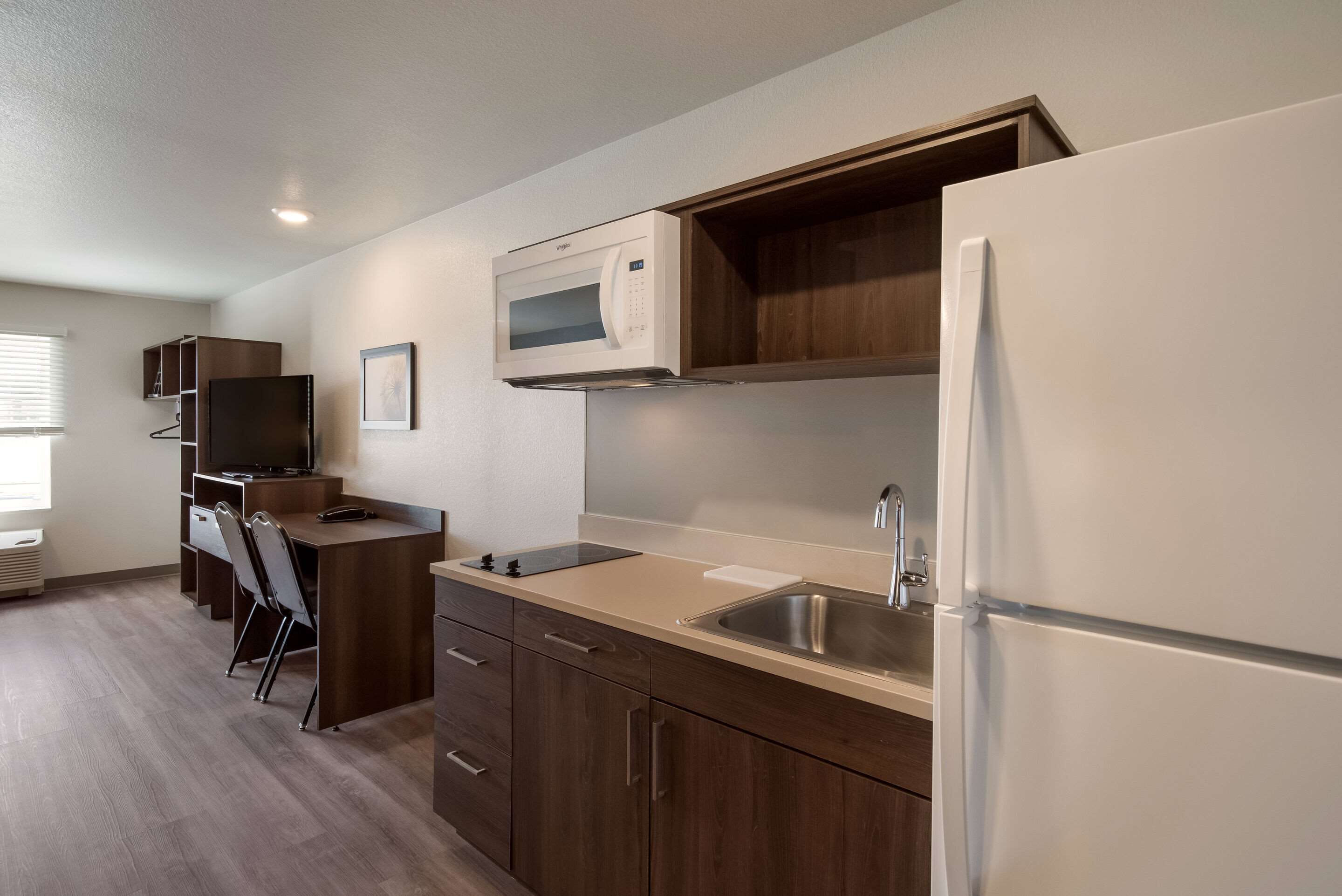 A compact kitchen with a microwave, refrigerator, sink, and wooden cabinets.