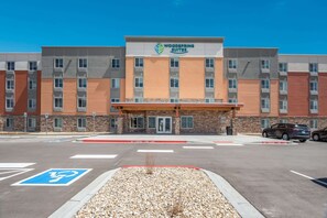 A multi-story hotel with a central entrance, marked by a sign for Woodspring Suites. - WoodSpring Suites Colorado Springs North - Air Force Academy (Colorado Springs)