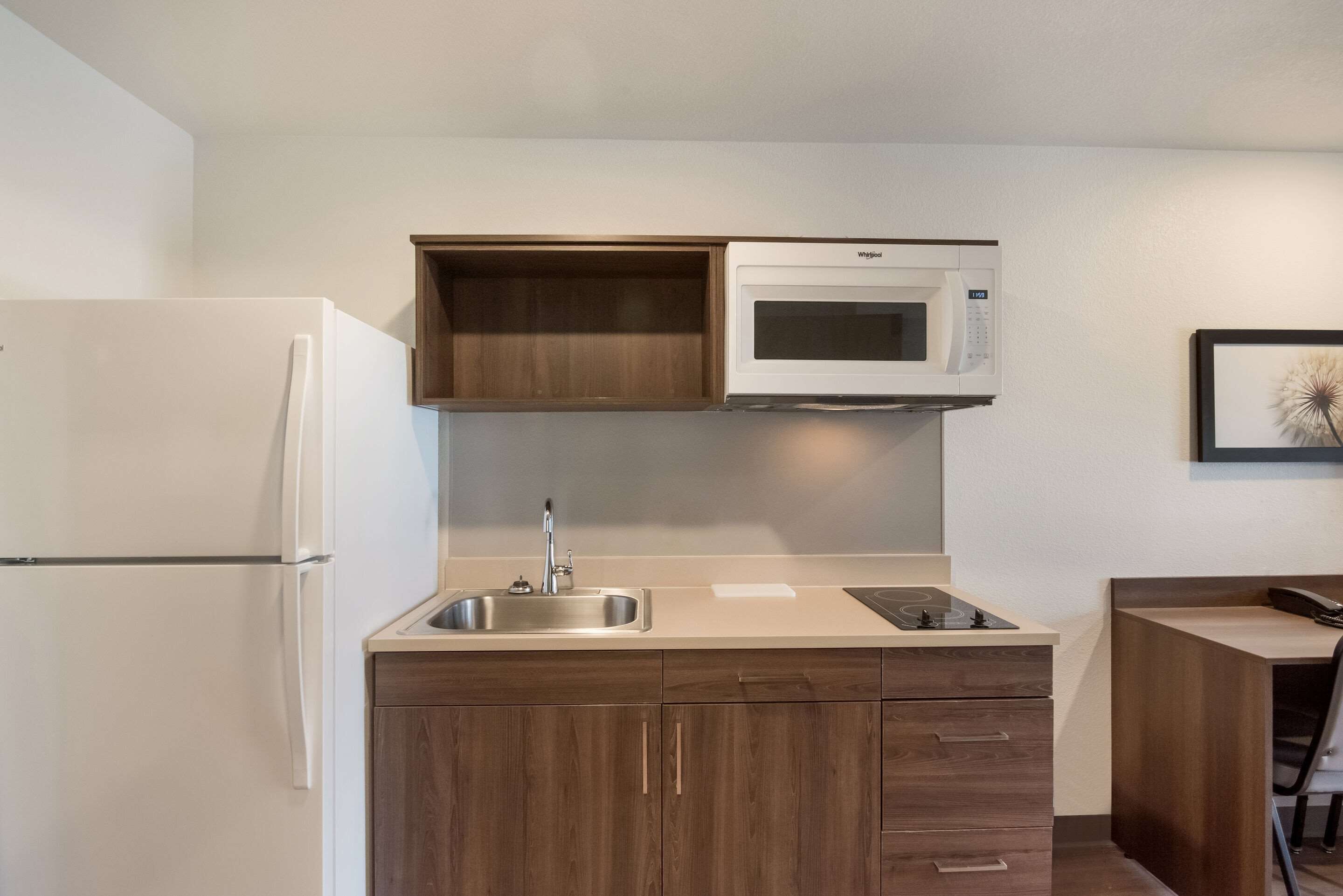 A compact kitchen with a built-in microwave, a sink, and wooden cabinets.
