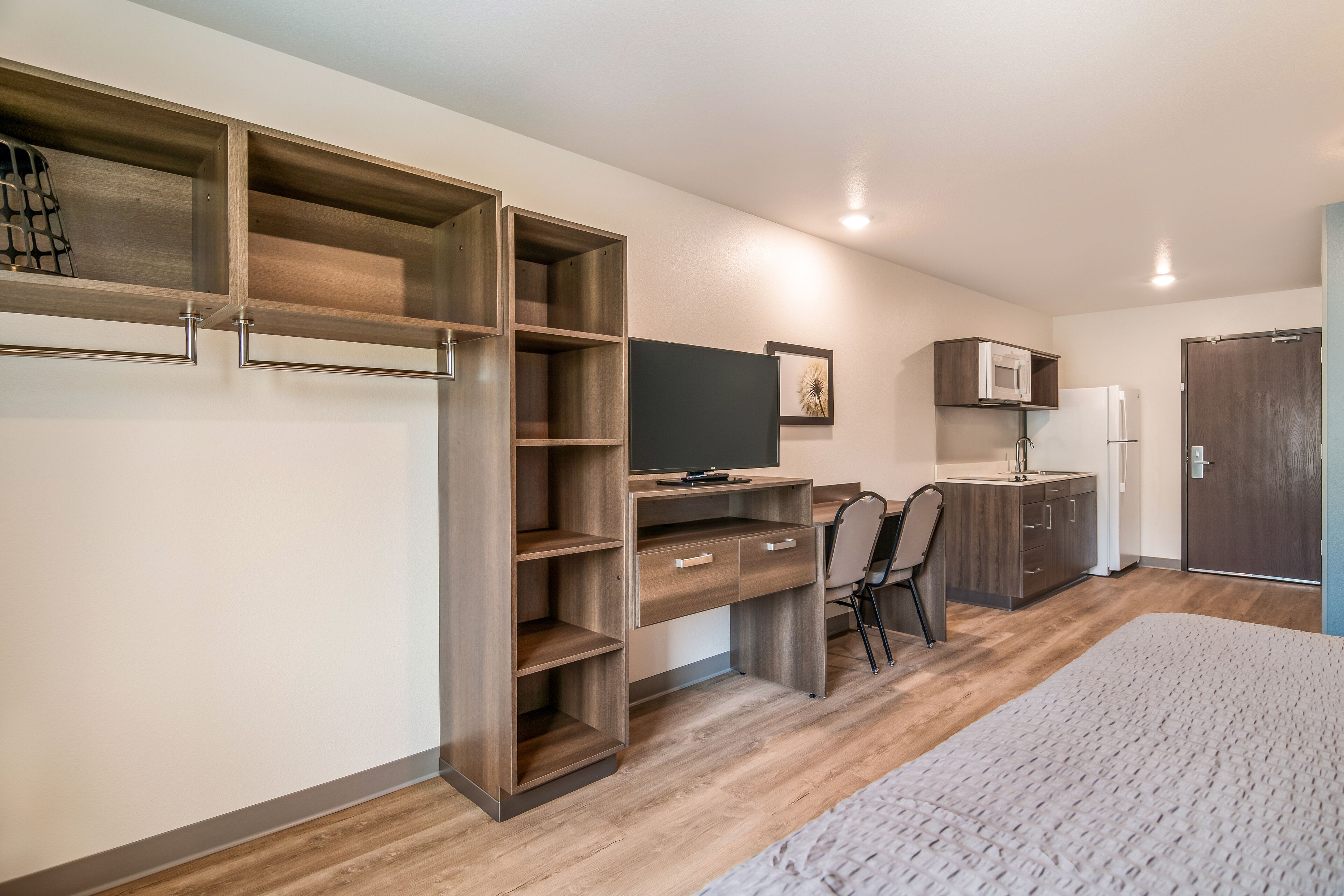 A compact bedroom with a bed, a desk, and a wardrobe.