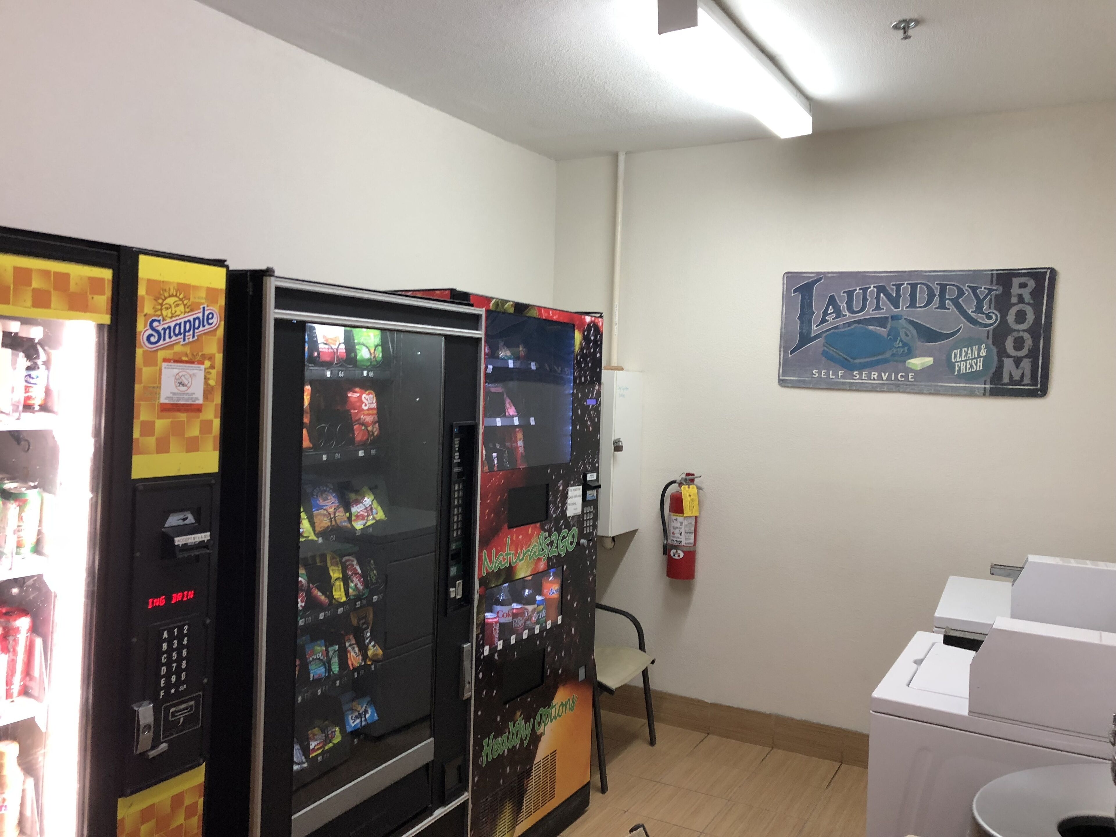 A room with vending machines, a fire extinguisher, and a laundry room sign.