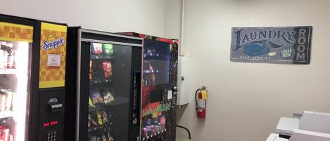 A room with vending machines, a fire extinguisher, and a laundry room sign.