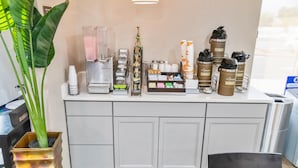 A modern reception area with a coffee machine, water dispenser, and various beverage containers. - Suburban Studios Brunswick of I-95 (Brunswick)