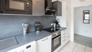 Uma cozinha moderna equipada com micro-ondas, fogão e forno, além de cafeteira e utensílios.