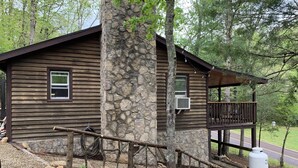 Eine rustikale Holzhütte mit einem Steinkamin, einer Holzdiele und einer Zuwegung mit Kies.