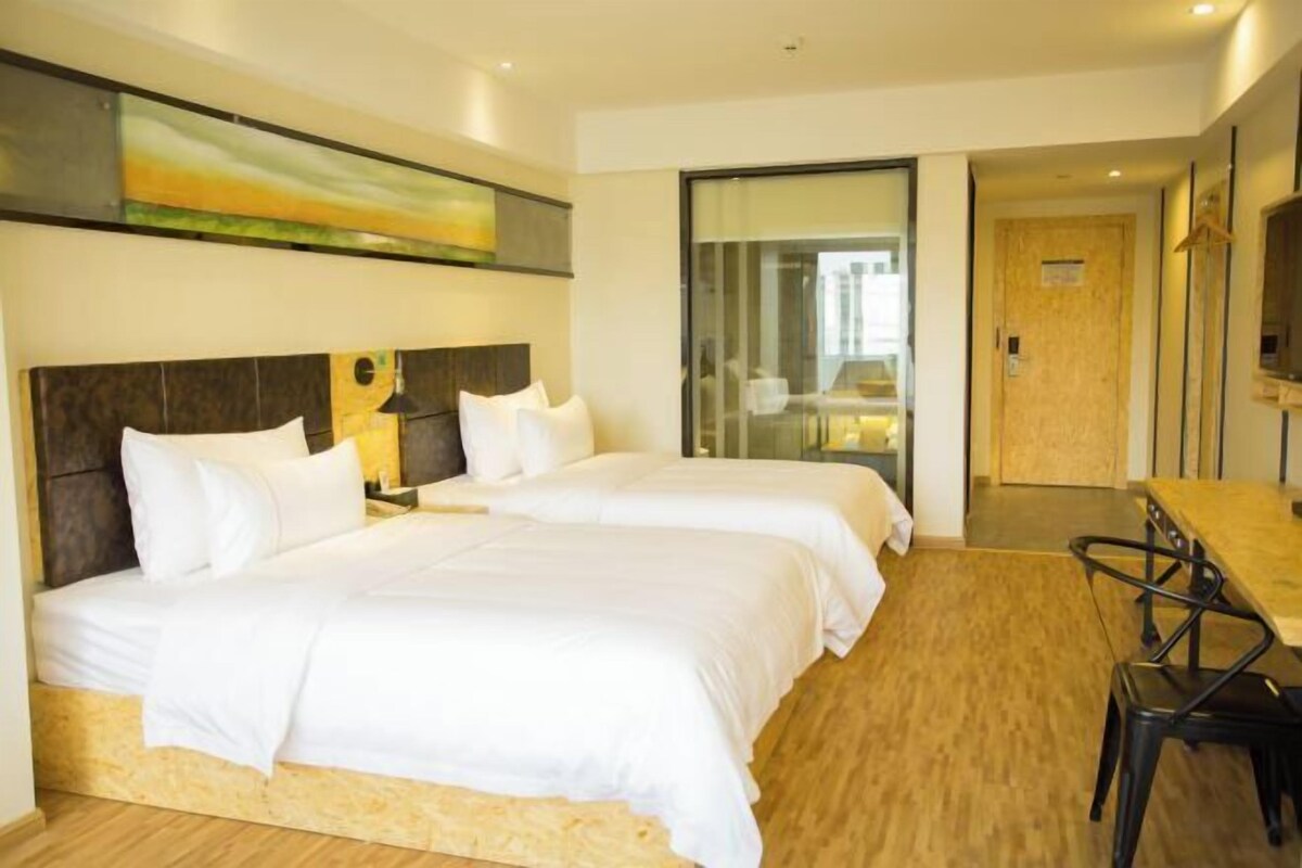 A hotel room with two beds, a dining table, and a view of the city.