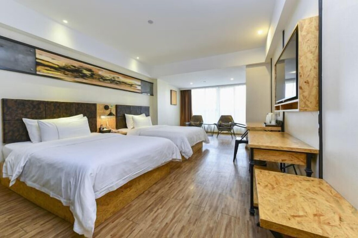 A hotel room with two beds, a desk, and a chair.