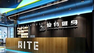 A modern fitness center with a wooden reception desk and a sign that reads 'RITE.'