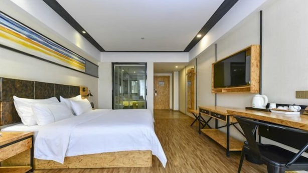A modern hotel room with a wooden bed, a desk, and a large mirror. - Meet Fashion Hotel (Huidong OCT Store) (Huidong)