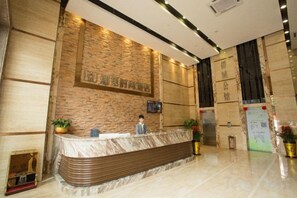 A hotel reception area with a marble counter, a receptionist, and a reception desk. - Meet Fashion Hotel (Huidong OCT Store) (Huidong)