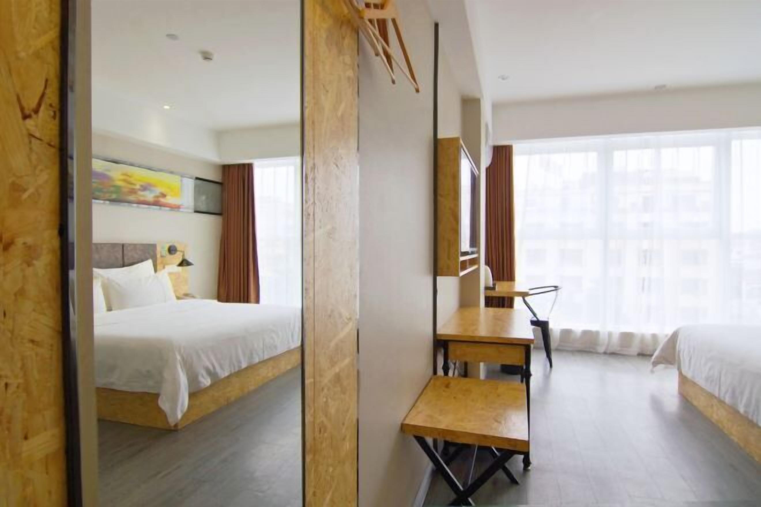 Habitación de hotel moderna con una cama grande, un escritorio y una ventana con vistas a la ciudad.