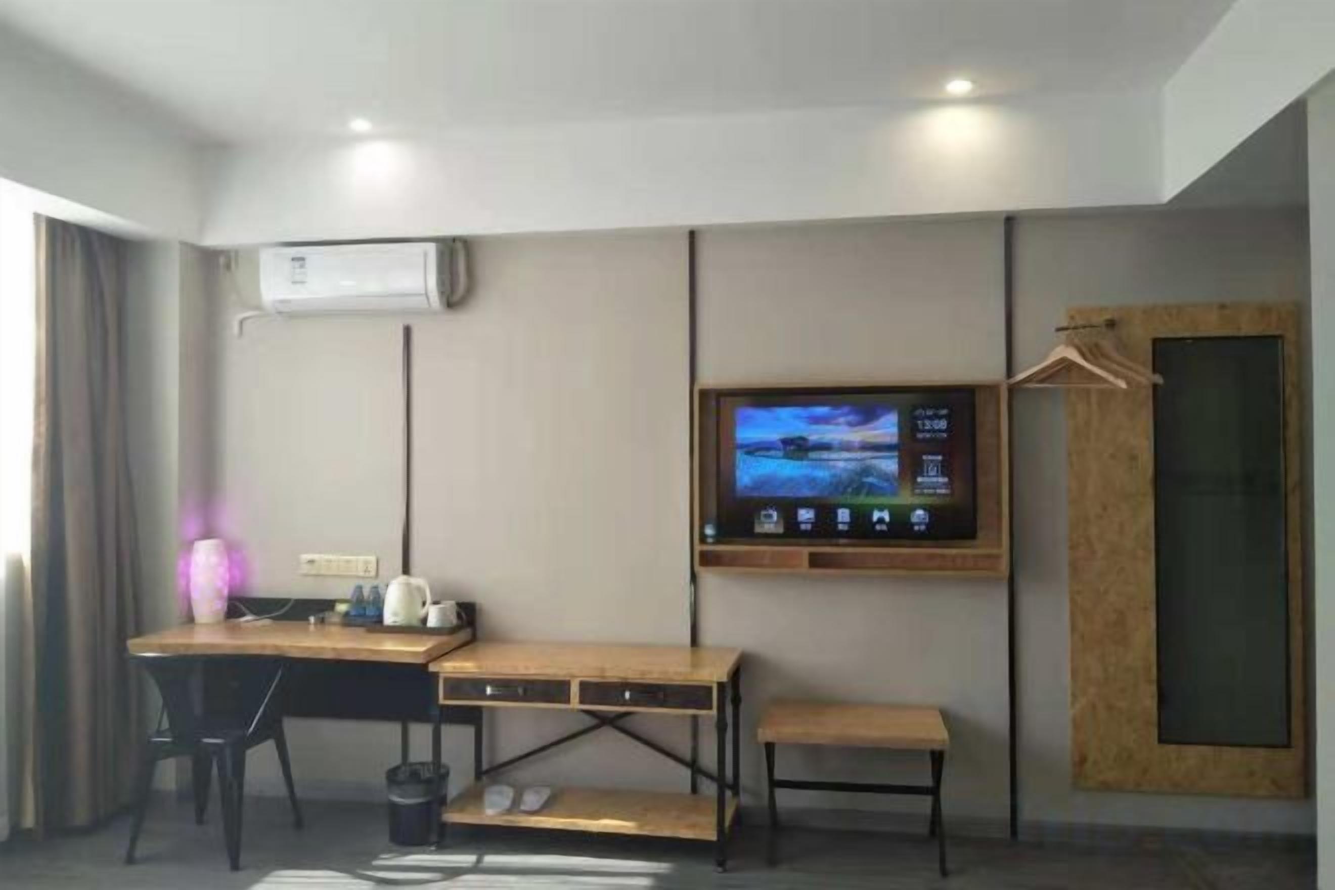 Ein Hotelzimmer mit Schreibtisch, Stuhl, Fernseher und einer Holztür.