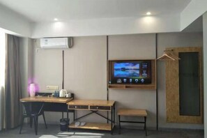 A hotel room with a desk, chair, TV, and a wooden door. - Meet Fashion Hotel (Huidong OCT Store) (Huidong)