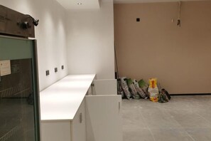 A room with a white counter, a glass door, and a beige wall. There are construction materials on the floor. - Meet Fashion Hotel (Huidong OCT Store) (Huidong)