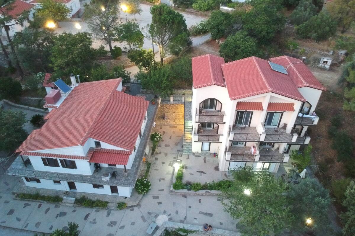 An aerial view of a residential area with two multi-story buildings featuring red-tiled roofs and white walls.