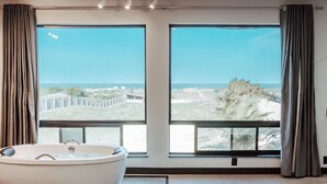 A modern bedroom with a large window, a bathtub, and a bed. - Peixe Gordo Hotel (Icapuí)