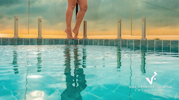 A person balancing on a tightrope over a pool, wearing a blue swimsuit. - Peixe Gordo Hotel (Icapuí)