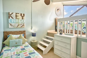 Une chambre à coucher comprenant un lit, une table de chevet, une commode, un escalier et une fenêtre donnant sur un paysage agréable.