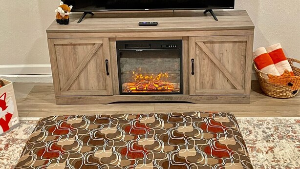 A living room with a fireplace, a television, and a patterned rug.