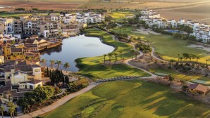 Un parcours de golf avec un plan d’eau, entouré d’immeubles résidentiels et de palmiers.