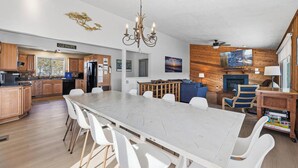 A spacious kitchen with a large island, wooden cabinets, and a chandelier. - Cair Paravel | 680 ft to the beach | (Virginia Beach)
