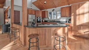A spacious kitchen with wooden cabinets, a central island with stools, and a high ceiling with exposed beams. - Durango Mountain House with Hot Tub and Views - great location (Durango)