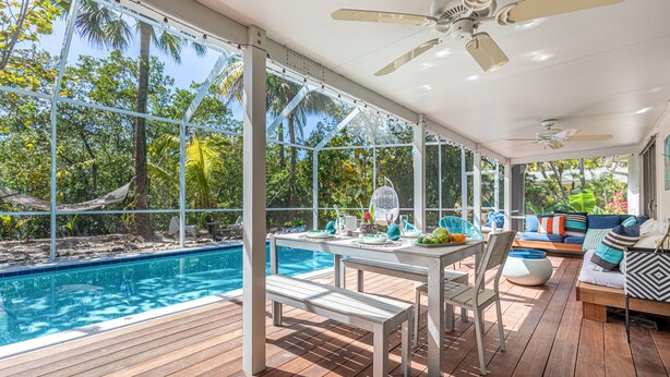 A covered outdoor area with a pool, wooden deck, seating, and ceiling fans. - ***NEW*** Beautiful Cottage Canal Front&Boat Dock (Sanibel)