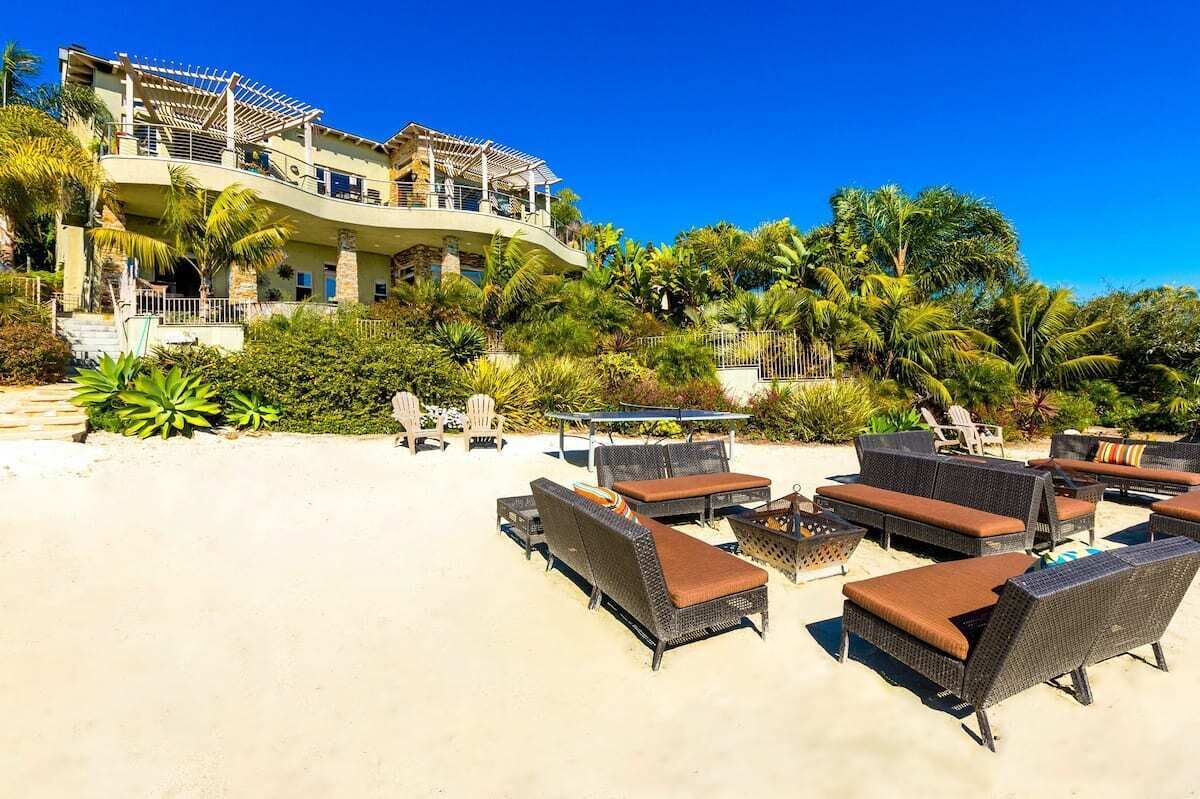 A beachfront property with outdoor seating and a large building with multiple balconies.