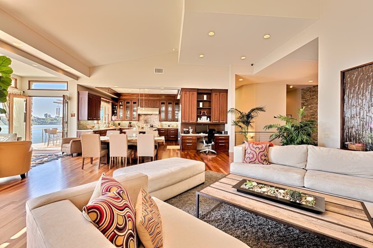 A spacious living area with a sofa, coffee table, and a view of the kitchen and dining area.