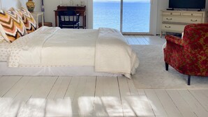 A bedroom with a large bed, a TV, a desk, and a view of the sea. - WATERFRONT Maine Historical Cottage with Separate Guest Cottage (Northport)