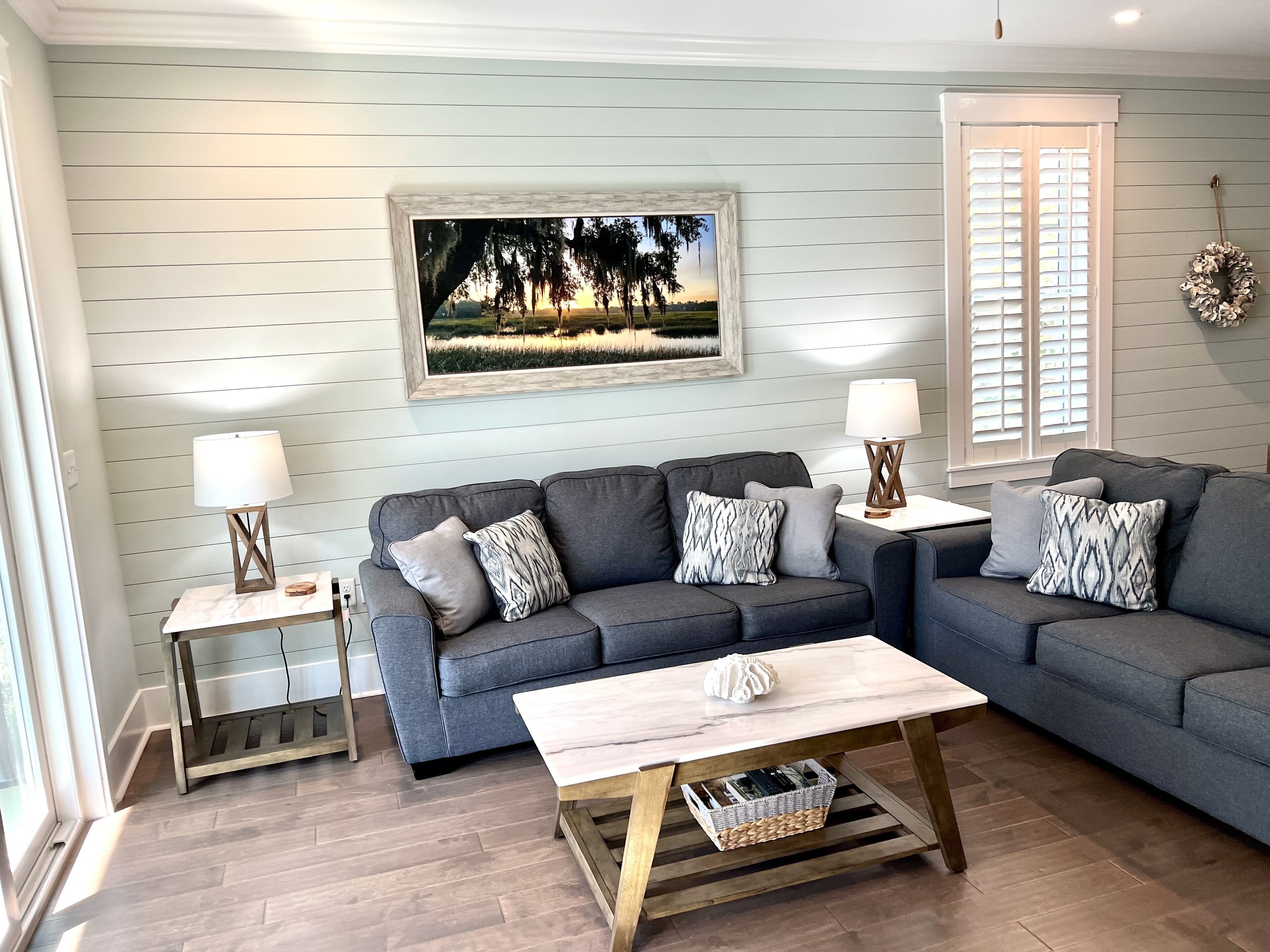 A living room with a grey sofa, two side tables with lamps, a wooden coffee table, and a framed picture on the wall.
