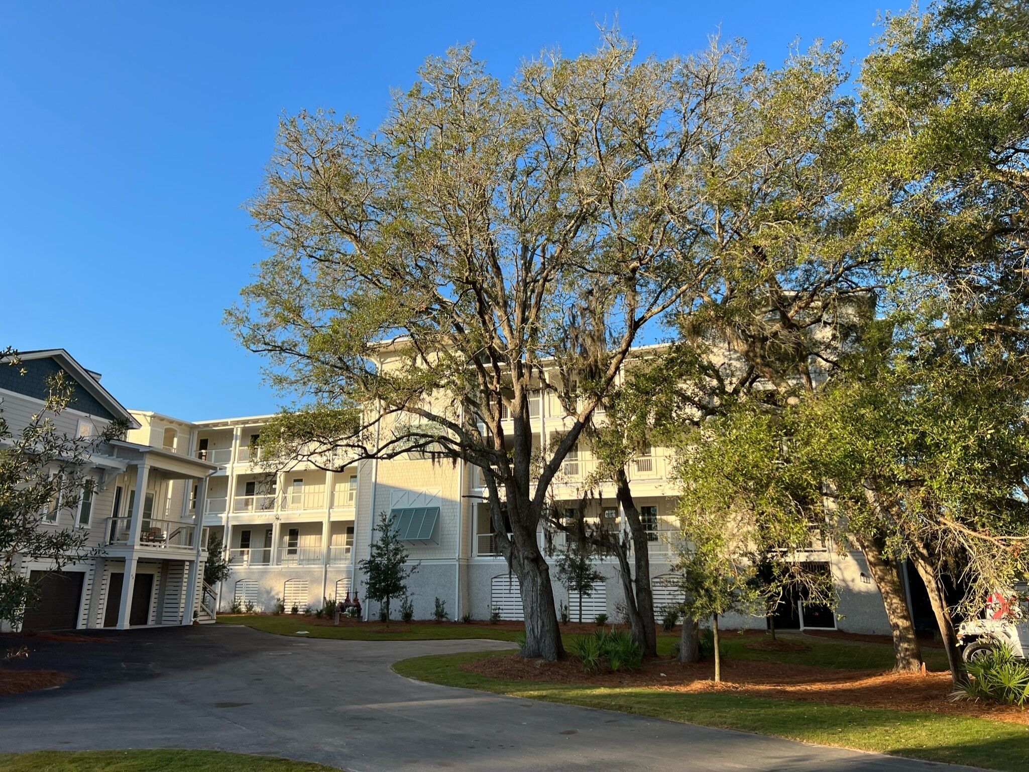 A residential building with a central courtyard, multiple balconies, and mature trees.