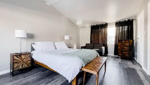 A modern bedroom with a bed, bedside tables, a bench, a chair, and a wardrobe. - Blocks from River & DT Missoula! University apt now offering mid-term rentals! (Missoula)