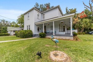 A two-story house with a porch, a bird sculpture, and a welcome sign. - Private historic district apt with pool-suite A (Ocala)