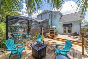 A covered outdoor deck with a pool, chairs, and a fire pit. - Private historic district apt with pool-suite A (Ocala)