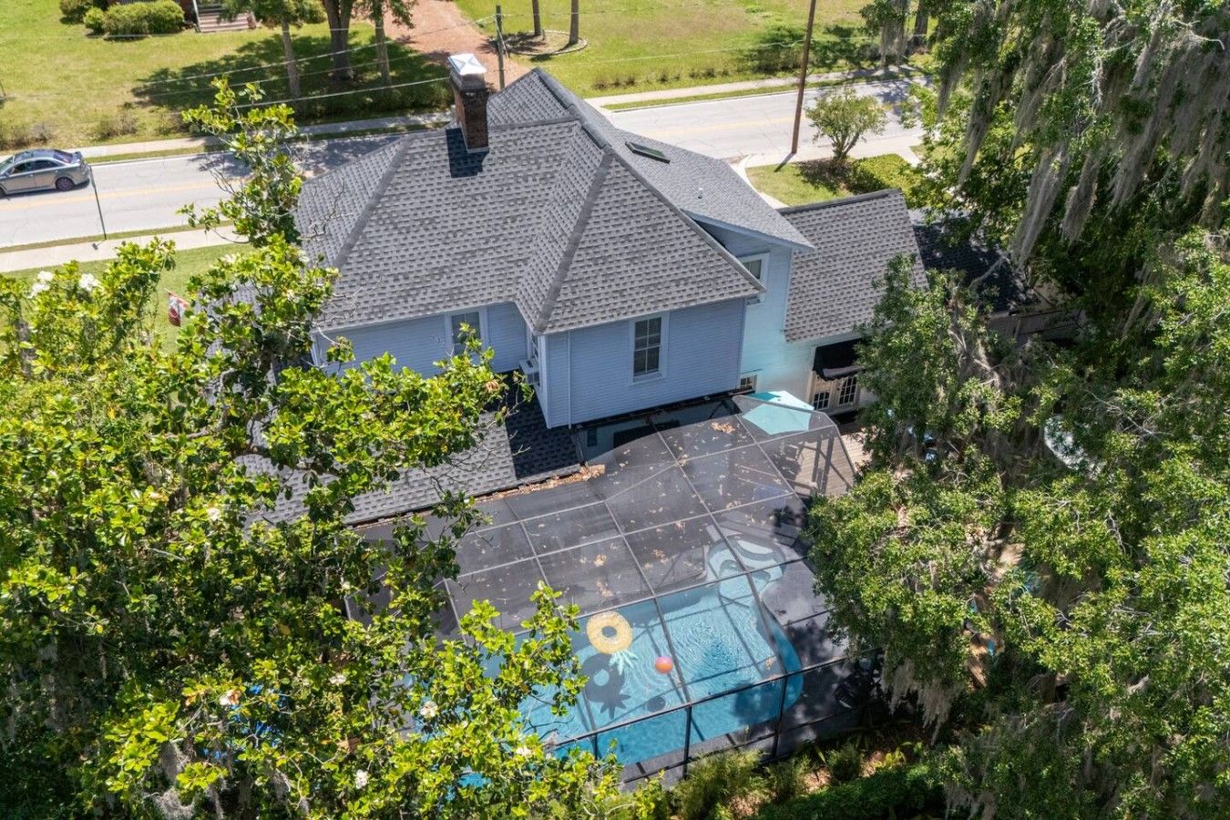Ein Haus mit Schwimmbad, umgeben von Bäumen und wolkenlosem Himmel.